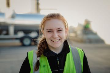 A young woman smiling with a high-vis jacket on.