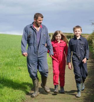 A Lakeland Dairies milk supplier walking with his two children on their farm.