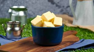 A small dish with cubes of Lakeland Dairies butter, with small milk churns in the background
