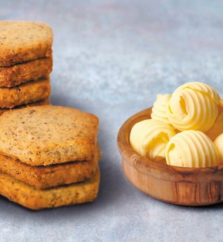Butter cookies stacked in a pile, made using Lakeland Dairies products, placed next to rolls of butter in a dish