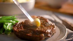 Lakeland Dairies butter being placed onto a steak with green beans