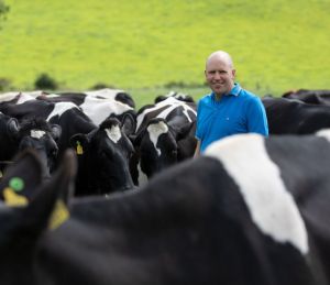 Farmer in middle of black and white cows