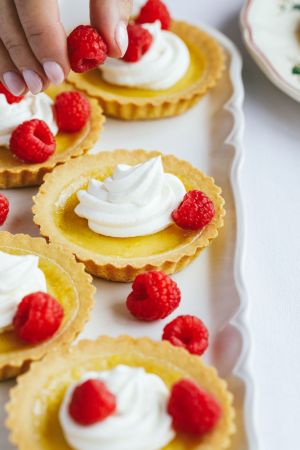 Mini lemon raspberry tartlets with cream and fresh raspberries