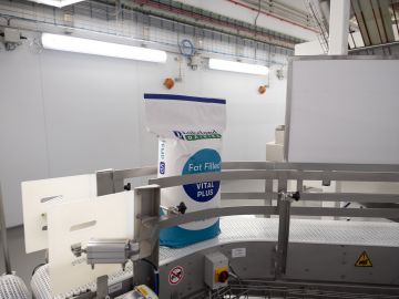 A bag of Lakeland Dairies fat filled milk powder on a conveyor belt.