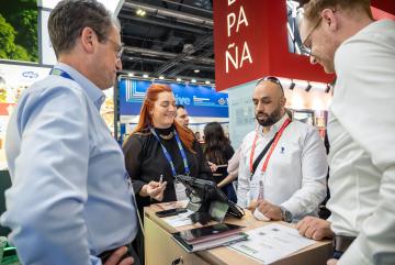 Four people smiling and standing around a desk at a Trade Show.