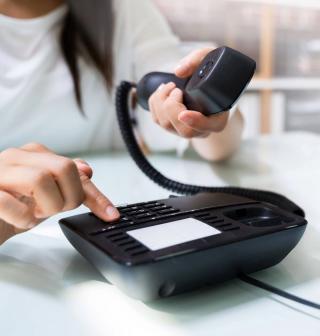 A woman dialing a number on a phone.