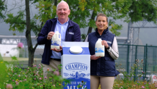 Lakeland Dairies Champion Milk cartons being held by two employees.