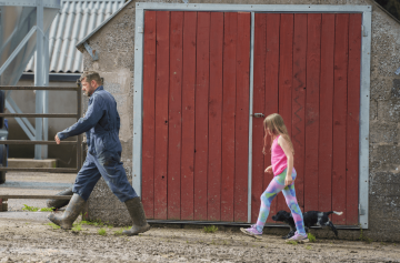 A father and daughter duo working on a farm with their dog.
